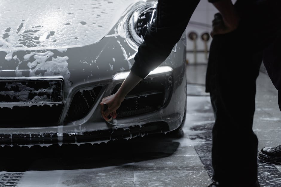 A close-up view of a car being meticulously washed with soap in a garage setting, emphasizing cleanliness and care.